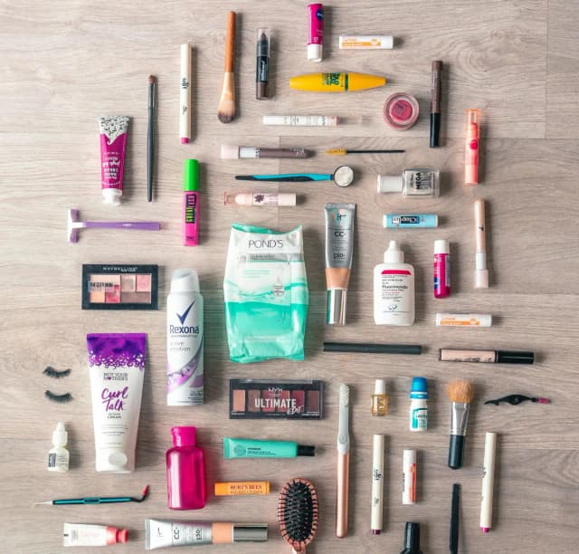 Various skincare and beauty products including bottles, jars, and tubes with ingredient labels visible, arranged on a bathroom counter